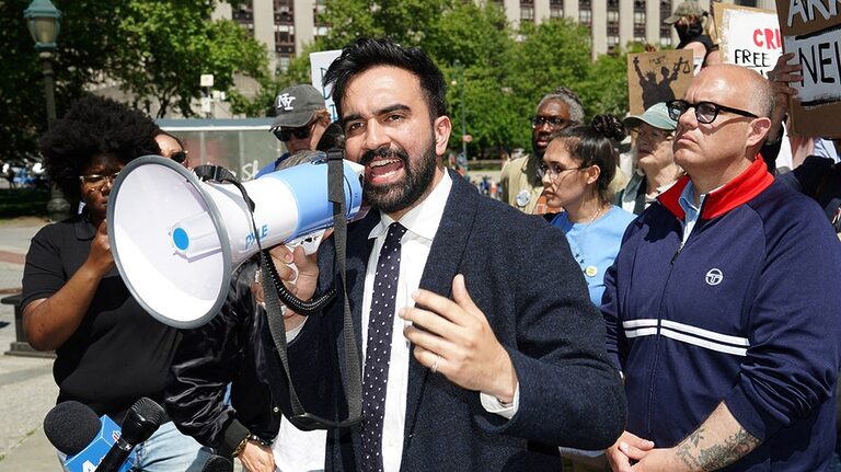 Zohran Mamdani speaking at a campaign rally with enthusiastic supporters